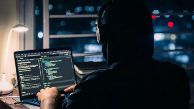 Muž se sluchátky kóduje na laptopu