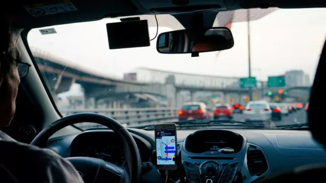Řidič za volantem vozu s navigací na smartphonu